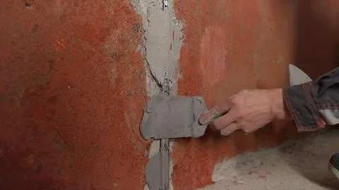 Construction worker's hand applying grey plaster to a wall joint with a tro.. Stock Photos