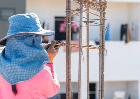 A construction workers hands using a tool to twist tie wire around steel reba Stock Photos