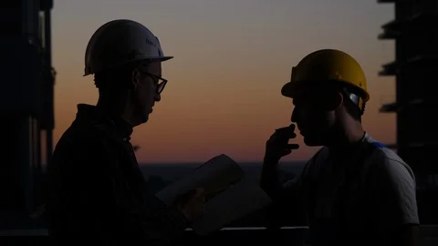 Construction workers having discussion at sunset. One smokes. Stock Footage 115453869
