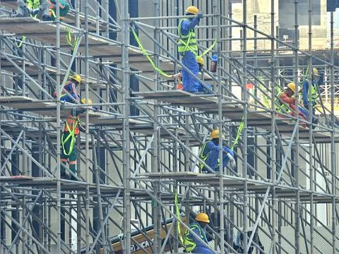Construction workers in high-visibility vests and hard hats are busy on a Stock Photos