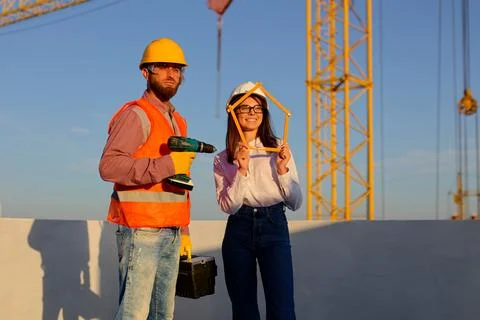 Construction workers holding tools at building site with crane Stock Photos