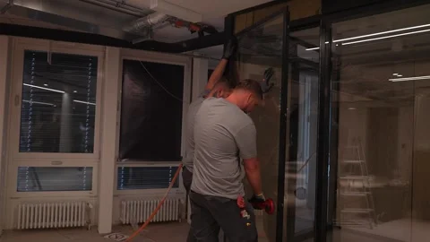 Construction workers install and secure a glass partition wall inside a modern Stock Footage 331304645