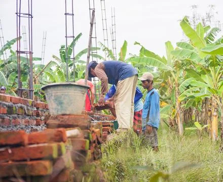 Construction workers install bricks and cement from rows of bricks on exterio Stock Photos