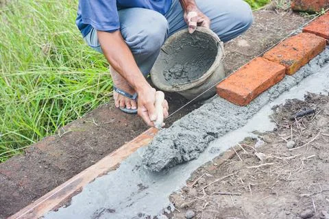 Construction workers install bricks and cement from rows of bricks on exterio Stock Photos