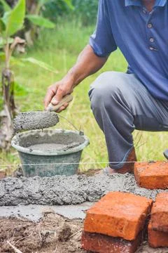 Construction workers install bricks and cement from rows of bricks on exterio Stock Photos