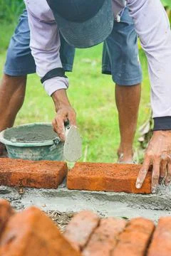 Construction workers install bricks and cement from rows of bricks on exterio Stock Photos