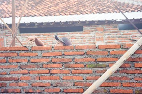 Construction workers install bricks and cement from rows of bricks on exterio Stock Photos