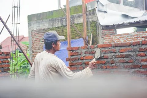 Construction workers install bricks and cement from rows of bricks on exterio Stock Photos