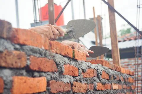Construction workers install bricks and cement from rows of bricks on exterio Stock Photos
