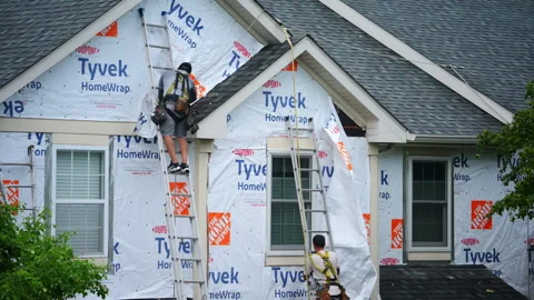Construction workers install exterior wall siding on a residential house Vídeos de archivo 327917602