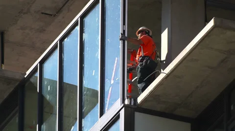 Construction workers install glass window at development site Stock Footage