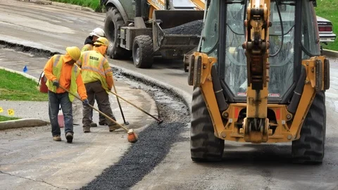 Construction workers installing asphalt patch on road wide shot Stock Footage 106365004