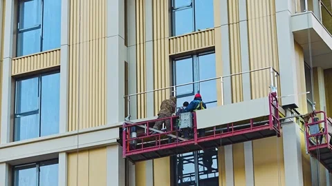 Construction workers installing facade elements on suspended platform Stock Footage 322056740