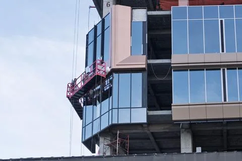 Construction workers installing glass facade on a high-rise building Stock Photos