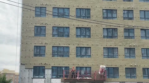 Construction workers installing insulation on a large building facade. Indu.. Stock Footage 342344882