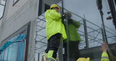 Construction Workers Installing a Large Glass Panel on a Modern Facade Stock Footage 315432555