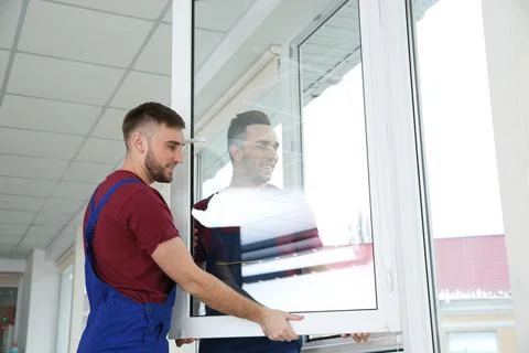 Construction workers installing plastic window in house 스톡 사진