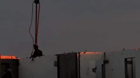 Construction workers installing precast panels at dusk with heavy machinery, Stock Footage 325698514