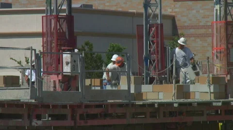 Construction workers lay cement block standing on scaffolding Vidéo 140102