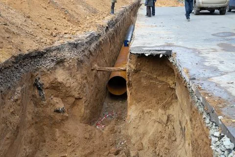 Construction workers lay a large water pipe under the road. Repair Stock Photos