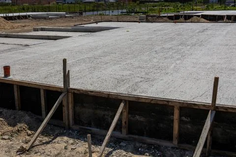 Construction workers lay a solid concrete slab foundation for a new house, .. Stockfoto's