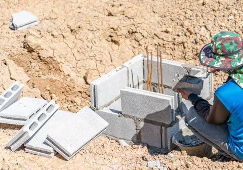 Construction workers laying the bricks to build the walls around the piles. Stock Photos
