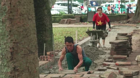 Construction workers laying bricks to pave the walkway Stock Footage 318142228