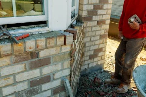 Construction workers laying clay brick to form brick wall at the constructi.. Stockfoto's