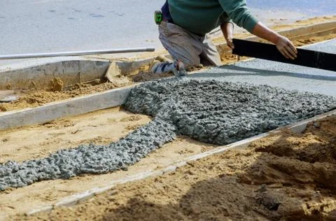 Construction workers laying concrete mixer with concrete mixer on sidewalk Stock-Fotos