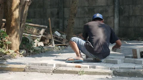 Construction workers laying paving blocks in a park, filmed in a sunny day Stock Footage 157412221