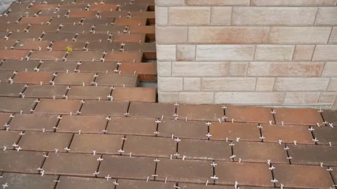 Construction workers laying paving stones around a brick pillar Vidéo 315664410