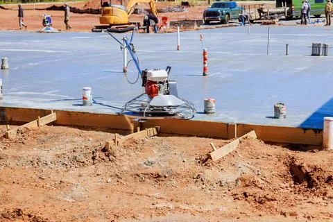 Construction workers leveling concrete slab finishing on construction site Stock Photos