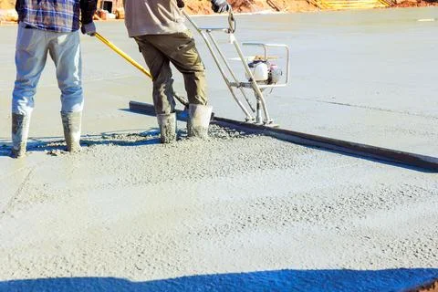 Construction workers leveling fresh concrete at building site during works day Stockfoto's