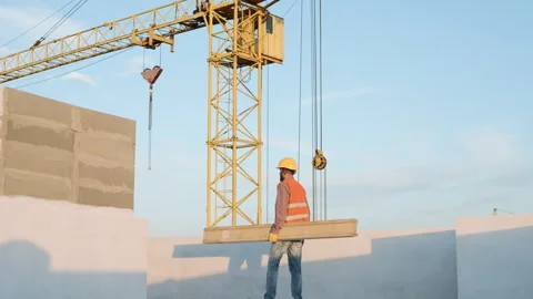 Construction workers lift beams at a construction site during sunset Stock Footage 286049548