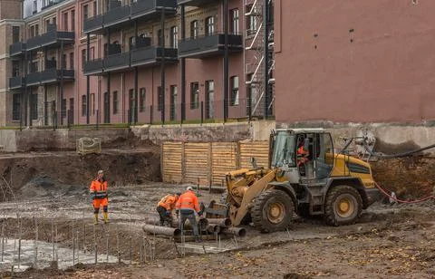 Construction workers loading old pipes on a large construction site Stock Photos