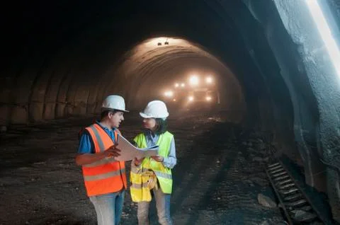 Construction workers looking at blueprint in tunnel Stock Photos