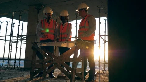 Construction workers at modern construction site. Smiling engineers look at a Stock-Footage 117633994
