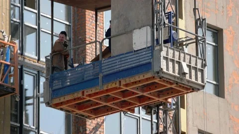 Construction workers move down on the elevator lift. Video stock 194935388