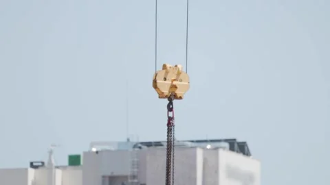 Construction workers operate a crane to lift materials at a building site in a Stock Footage 338246011