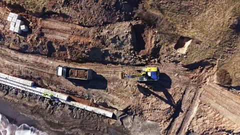 Construction workers operate heavy machinery on a site with trucks and digging Stock Footage 331333233