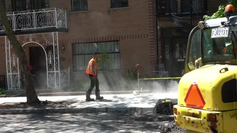 Construction workers operate heavy machinery and concrete cutters on an urban Stock Footage 334563815