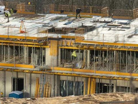 Construction workers operating on a building site roof with scaffolding and Stock Photos