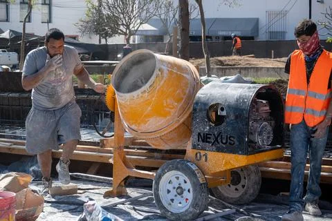 Construction workers operating a cement mixer at a building site in Zapopan Stock Photos