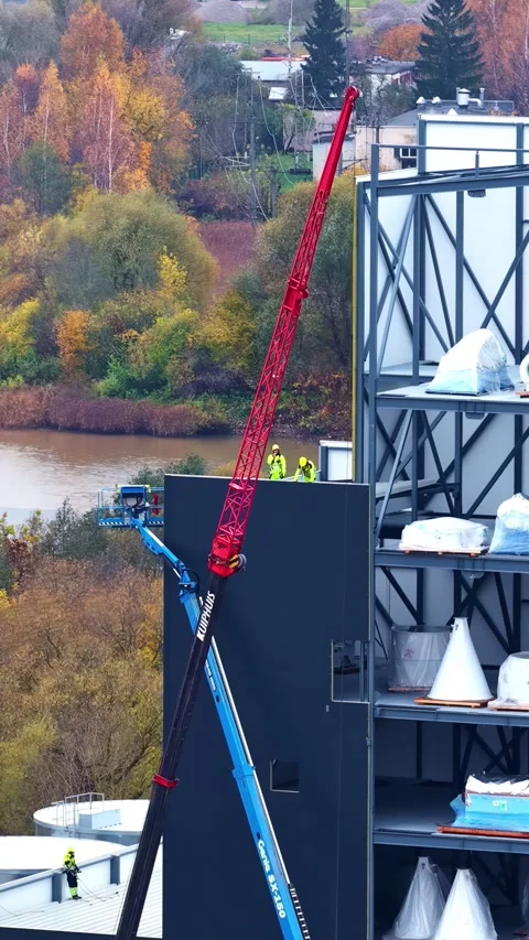 Construction workers operating crane and boom lift on industrial building site Stock Footage 336240499