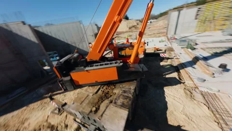 Construction workers operating heavy orange crane lifting steel beams, preparing Stock Footage 306397060