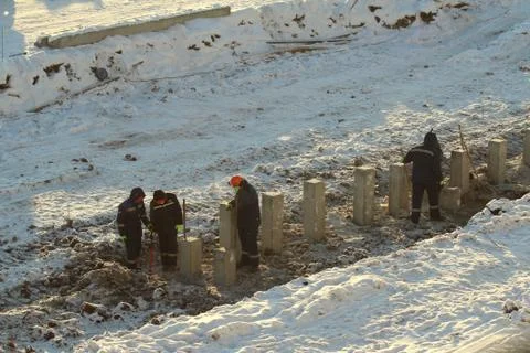 Construction workers in overalls in orange helmets work at a construction sit Stock Photos