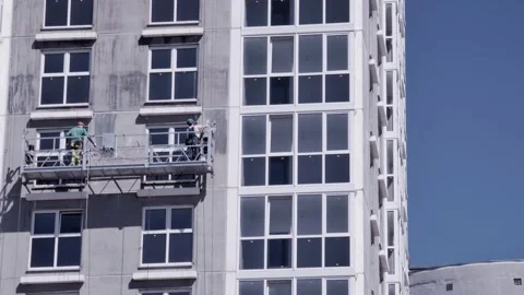 Construction workers perform facade installation and maintenance from suspended Stock Footage 342230812