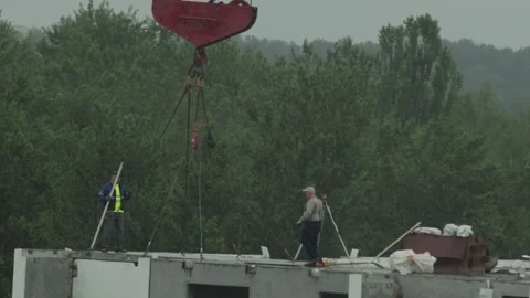 Construction workers perform land surveying and crane operations on building Stock Footage 339865850