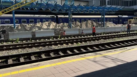 Construction workers perform railway track maintenance beside a passenger train Stock Footage 339910358