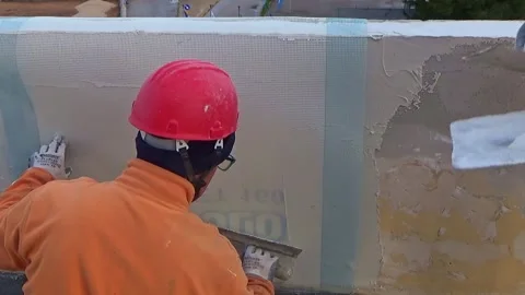 Construction workers place a plastic reinforcing mesh under the plaster morta Video stock 301640854